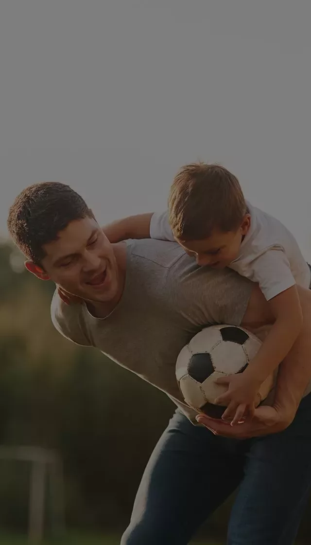 Dad son playing football in park
