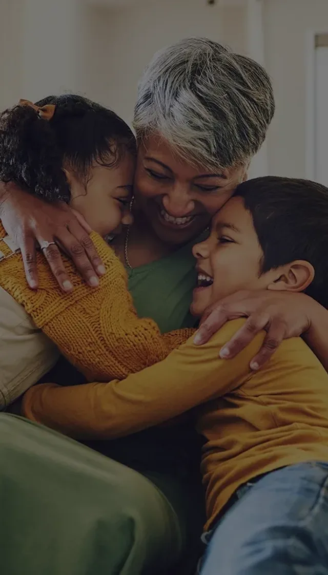 Grandma hugging grandchildren on sofa