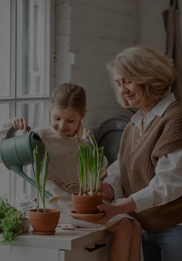 Girl watering plants with elderly granny
